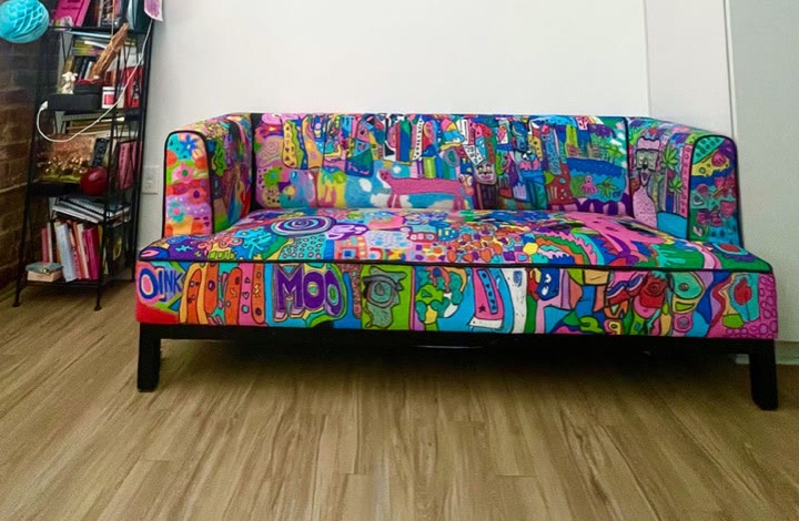Klo's real couch, hand-painted with paint markers in bright folk-art: city blocks, flowers, a frog, a cow and a big MOO.